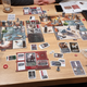 Look at this sprawl! And that’s just with two players! If there were four you’d need to be adding two more of those big red player mats, and all the cards and equipment to go along with them.